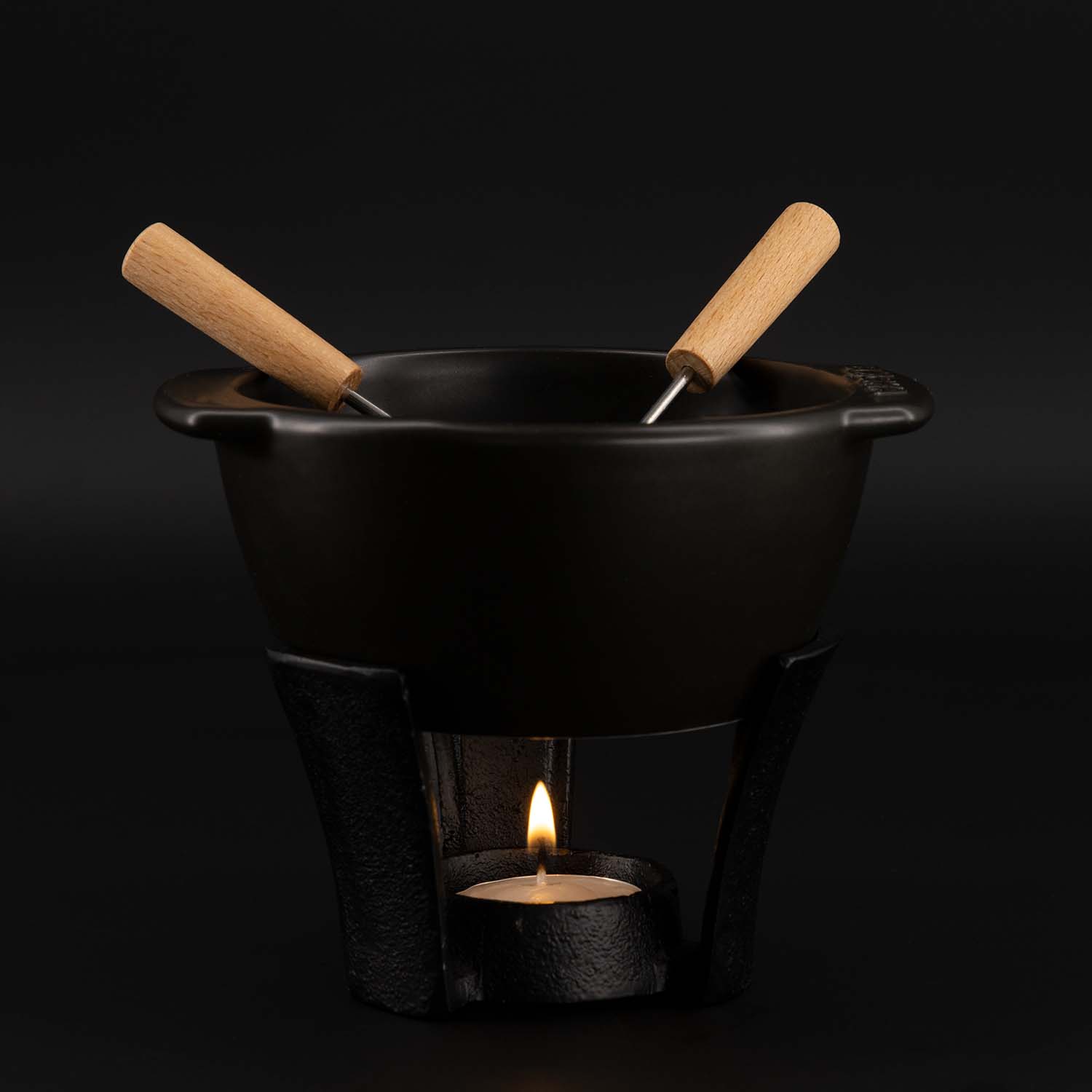 Zwarte fondue met kaars op zwarte achtergrond